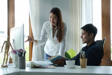 Kendine güvenen iş kadını bilgisayar ekranına işaret ediyor ve pazarlama verilerini meslektaşına anlatıyor..