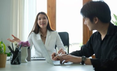 Kendine güvenen Asyalı bayan takım lideri iş arkadaşlarıyla fikir ya da iş planı paylaşıyor..