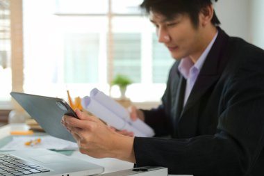 Mühendis erkek dijital tablet kullanıyor ve mimari plan için ofiste çalışıyor..