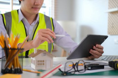 Ofisteki mimari proje üzerinde çalışan dijital tabletin bilgilerini kontrol eden mühendis.