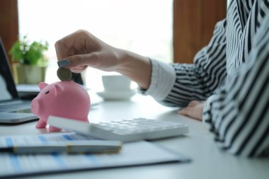 Domuz kumbarasına para koyan bir kadının kesilmiş görüntüsü. Gelecek için para biriktirmek, iş yatırımları finansman muhasebesi.
