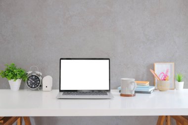 Bilgisayar bilgisayarı, kırtasiye malzemesi, kahve fincanı ve ev bitkisi beyaz masada. Metin iletiniz veya bilgi içeriğiniz için boş ekran. 
