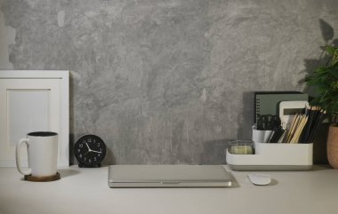 Creative workplace with computer laptop, coffee cup, alarm clock and books on white table.	