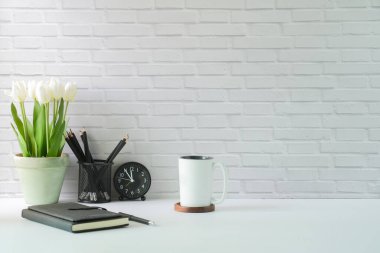 Stylish workplace with stationery, picture frame and houseplant on white table.	