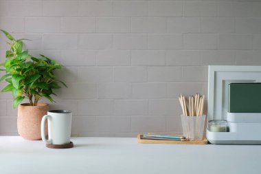 Resim çerçeveli, kahveli, kırtasiyeli ve beyaz masalı rahat bir iş yeri. Merkez, kopyalama alanı.