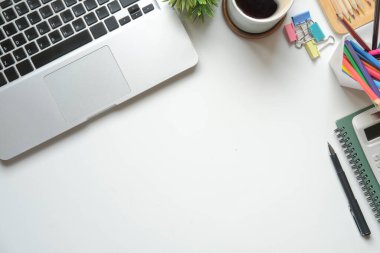 Laptop bilgisayar, kahve fincanı ve kırtasiye malzemeleri beyaz ofis masasında. Düz yatış, Üst Görünüm.