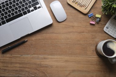 Laptop bilgisayar, kahve fincanı, saksı bitkisi ve hesap makinesi ahşap masada. Düz konum, Üst görünüm, Boşluğu kopyala.