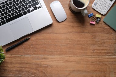 Laptop bilgisayarı, kahve fincanı, hesap makinesi ve tahta masadaki not defteri olan basit bir iş yeri. Düz, Üst Görünüm, Boşluğu Kopyala.