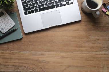 Bilgisayar dizüstü bilgisayar, kahve fincanı, defter ve hesap makinesi ahşap masada. Düz konum, Üst görünüm, Boşluğu kopyala.