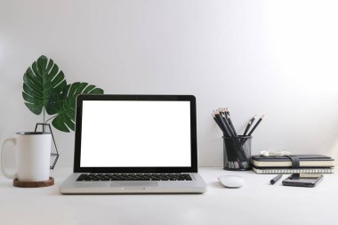 Mockup laptop with empty display, coffee cup, books and picture frame on white table.	