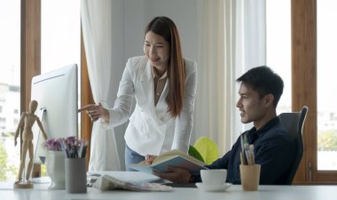 Parlak ofiste birlikte çalışırken bilgisayardaki finansal verileri analiz eden genç iş adamları.