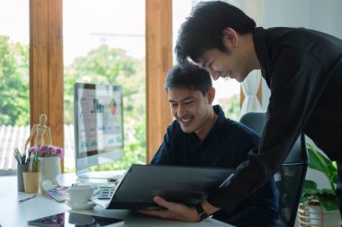 Genç iş adamları modern ofiste yeni bir iş projesi üzerinde tartışıyorlar.