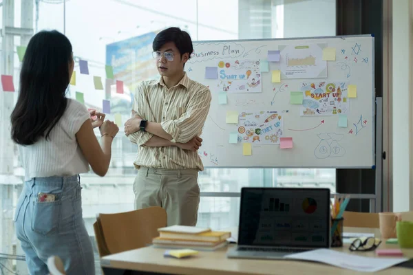 İki genç iş arkadaşı modern ofiste yaratıcı projeyi tartışıyor..