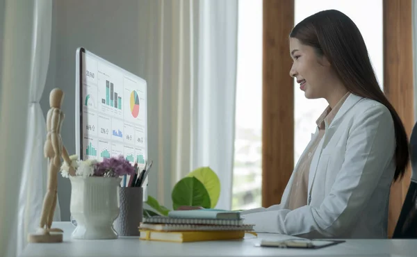 明るいオフィスに座って コンピュータ画面上の財務グラフを分析する集中女性ビジネスリーダー — ストック写真