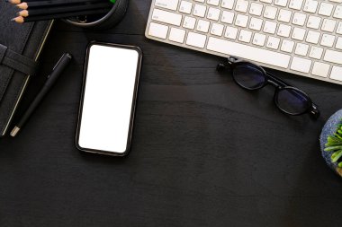Flat lay mobile phone, computer, coffee cup and stationery on wooden table.	