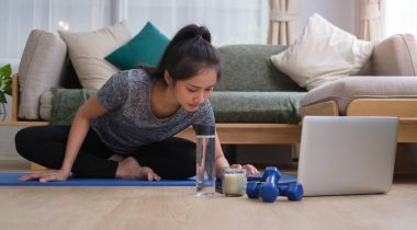 Spor yapan genç bir kadın sabah antrenmanı sırasında bilgisayar kullanıyor. Spor, spor ve sağlıklı yaşam tarzı konsepti.