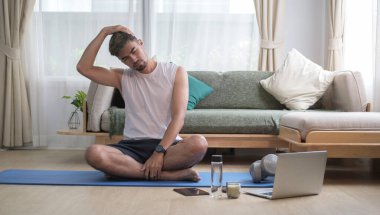 Evde antrenmandan önce yakışıklı bir adam ısınıyor. Sağlıklı yaşam tarzı kavramı.