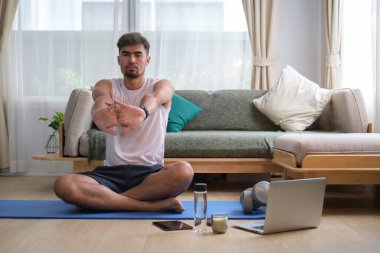 Antrenmandan önce kollarını esneten genç bir adam. Fitness ve sağlıklı yaşam tarzı.