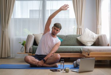 Evde antrenman yapmadan önce ısınma sırasında yan yatan yakışıklı adam. Sağlıklı yaşam tarzı kavramı.