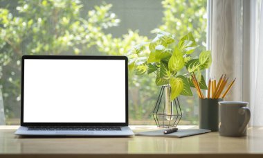 Boş ekranlı bilgisayar bilgisayarı, kahve fincanı, kalem tutacağı ve ahşap masadaki ev bitkisi..