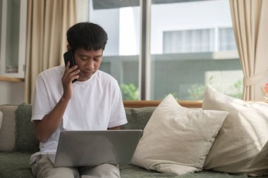 Happy asian man using smartphone in living room.	