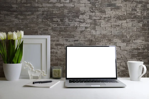 Laptop bilgisayarı, ev bitkisi ve resim çerçevesi olan modern bir iş yeri. Metin reklamı için boş ekran.