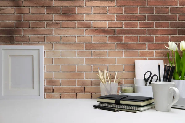 Boş çerçeve, kalem tutacağı ve beyaz masada laleleri olan kadınsı bir iş yeri. Bilgi içeriğiniz için alanı kopyalayın.