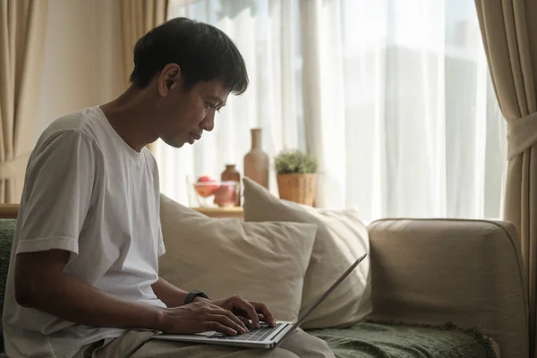Усміхнений Азіатський Чоловік Сидить Дивані Використовуючи Ноутбук — стокове фото