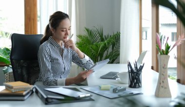 Pretty young female office worker using computer tablet at modern workplace.	