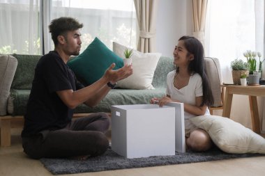 Taşındıktan sonra kutuları açan neşeli genç çift. Emlak kirası ve mülkiyet kavramı.