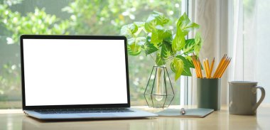 Home office desk with computer laptop, coffee cup and houseplant on wood table.	