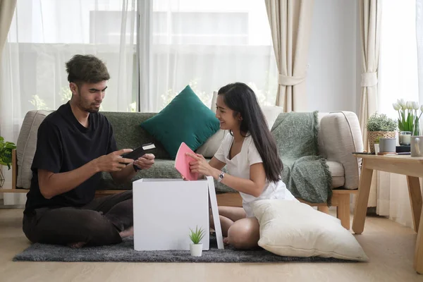 Taşındıktan sonra kutuları açan mutlu genç çift. Emlak kirası ve mülkiyet kavramı.