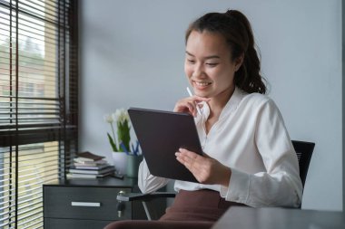 Woman entrepreneur using digital tablet while sitting at her workplace.	