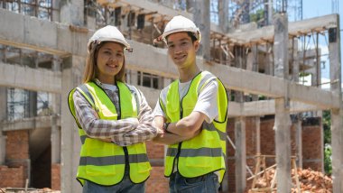 İnşaat alanında duran kasklı ve sarı yelekli kendinden emin mühendisler..