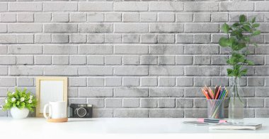 Fotoğraf çerçeveli, ev bitkisi, kahve fincanı ve kalem tutacağı olan yaratıcı bir iş yeri. Reklam metni için alanı kopyala.