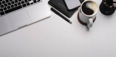 Office desk with smart phone, laptop computer, notebook and coffee cup. Copy space.	