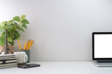 Laptop bilgisayarı, kahve fincanı, ev bitkisi ve kırtasiye malzemesi olan minimum iş yeri. Metnin için boşluk kopyala.