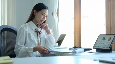 İş kadını portresi büro masasında oturuyor ve belgeleri kontrol ediyor..