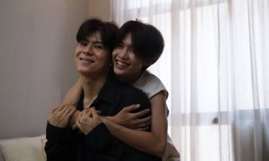 Sevgi dolu eşcinsel çift yatakta oturuyor ve sarılıyorlar, birbirlerine sarılıyorlar. LGBT topluluğu, eşit haklar, güzellik ve sevgi.