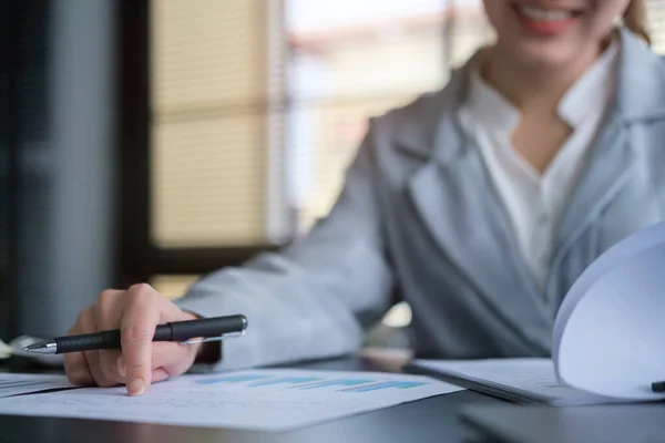 Focuses young female financial adviser checking financial report at office desk.