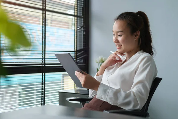 Gülümseyen Asyalı Kadını Modern Ofiste Oturuyor Belgeleri Okuyor — Stok fotoğraf