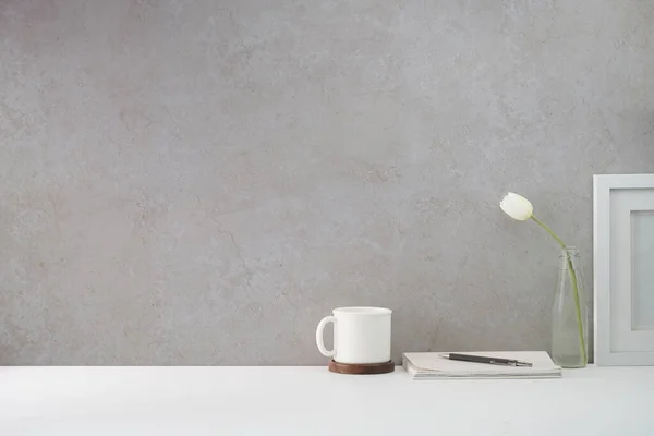 Stock image Minimal workplace with coffee cup, flower pot and picture frame on white table. Copy space for your text.