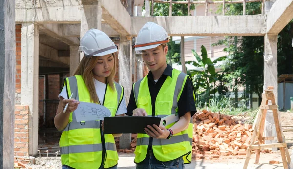 两名戴着安全帽的建筑师在建筑工地讨论 测量布局 — 图库照片