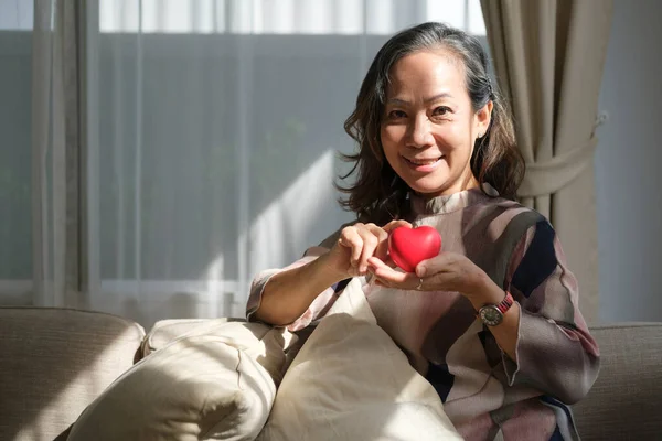 Kalbi düzgün ve kameraya gülümseyen yaşlı bir kadın. Yaşlı sağlık hizmetleri, sigorta kavramı.