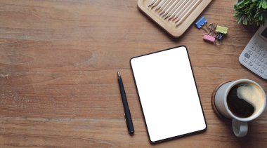 Üstünde boş ekran, kitaplar, kahve fincanı ve ahşap masa üzerinde saksı bitkisi olan dijital tablet. Boşluğu kopyala.