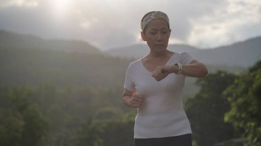Mutlu orta yaşlı kadın koşuyor ve performansını kontrol ediyor. Kalp atış hızı, Sport, egzersiz ve doğa sporları..