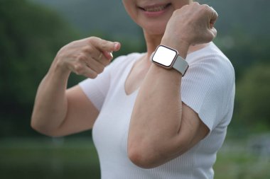 Bilek akıllı saatini gösteren mutlu emekli kadın sabah antrenmanından sonra yakılan kalorilerle gurur duyuyor. Fitness, sağlıklı yaşam tarzı ve aktivite konsepti. 