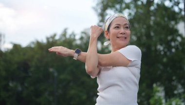Güneşli bir günde yeşil bir parkta koştuktan sonra gülümseyen orta yaşlı bir adam. Emeklilik, fitness, sağlıklı yaşam tarzı, spor ve aktivite konsepti.