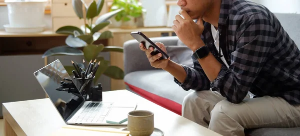 Asian Male Freelancer Working Home Laptop Using Smart Phone — стокове фото