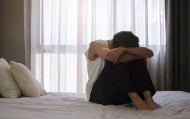 Mutsuz erkek, yatak odasında oturmuş çaresiz, yalnız ve depresyondan acı çekiyor. Sefil, yalnız, depresyon, akıl sağlığı konsepti.